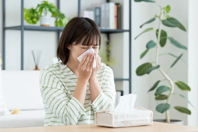 花粉アレルギーで鼻水をかむ女性